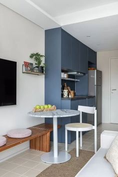 a living room and kitchen area with a table, chairs, television and couches