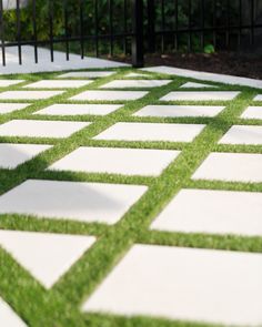 an outdoor walkway with grass and white tiles