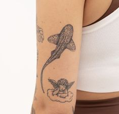 a woman with a tattoo on her arm has a shark and angel above her head