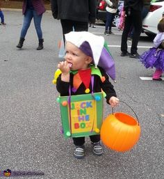 a little boy dressed up as a clown with a trick on his face and holding an orange bucket