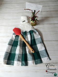 a green and white checkered dress with a red spatula next to it on a wooden table