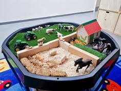 a toy farm set up with animals and toys in the back ground, on top of a play table