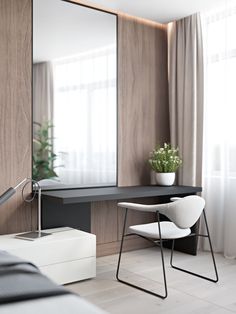 a bedroom with a desk, mirror and plant in the corner on the wall next to it