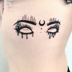 a woman's lower back with eye lashes and moon tattoo on her left side