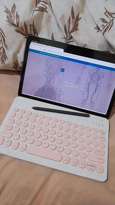 a laptop computer sitting on top of a bed next to a keyboard and mouse pad