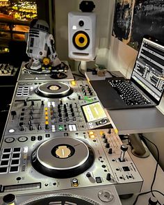 a laptop computer sitting on top of a dj's desk next to mixing equipment