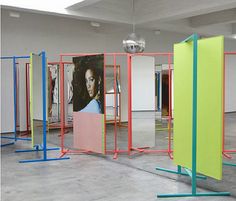 an empty room with multiple colored partitions in the middle and a poster on the wall