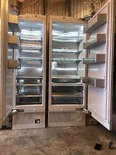 two stainless steel refrigerators side by side with their doors open in a warehouse setting