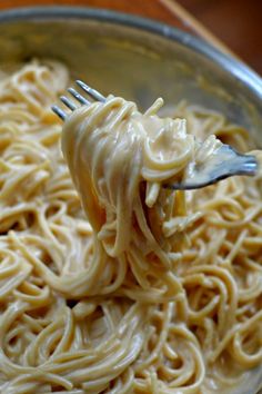 a fork full of pasta being held by someone's hand with the word easy cheesy spaghetti on it