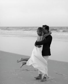 a bride and groom kissing on the beach