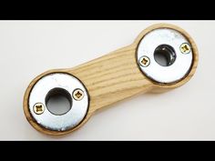 two metal knobs are attached to a wooden handle on a white surface with gold rivets