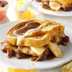 two plates topped with french toast covered in caramel and apple slices on a table