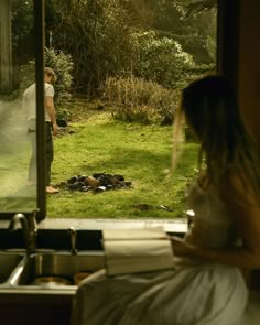 a man and woman standing in front of a kitchen window looking out at the yard