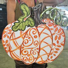 a woman is holding two painted pumpkins