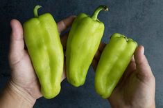 three green peppers held in two hands