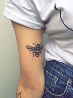 a woman's arm with a bee tattoo on it