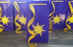 purple bags with yellow swirls and sun designs are lined up on a wooden floor