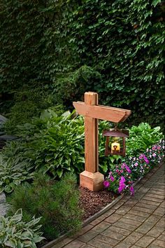 a wooden cross sitting in the middle of a garden