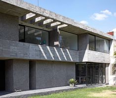 a concrete building with several windows on the side and grass in front of it,