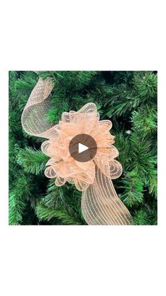 an ornament hanging from the top of a christmas tree with ribbons on it