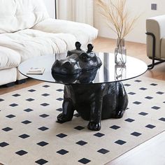 a glass table with a black dog figurine on it in front of a white couch