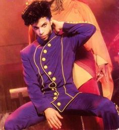 a man sitting on top of a chair next to a woman in a purple suit