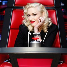 a woman sitting in a red chair with her hand on her chin and looking at the camera