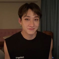 a young man wearing a black shirt and earrings