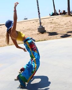 a woman riding a skateboard down the side of a cement covered slope next to palm trees