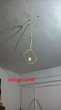 an overhead light fixture with wires attached to the ceiling in a room that is white