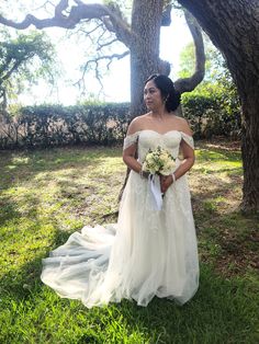 a woman in a wedding dress standing under a tree