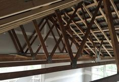 the inside of a building that is being built with wooden beams and wood rafters