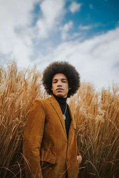 a man with an afro standing in tall grass