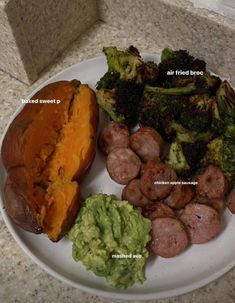 a white plate topped with potatoes, broccoli and other foods on top of a counter