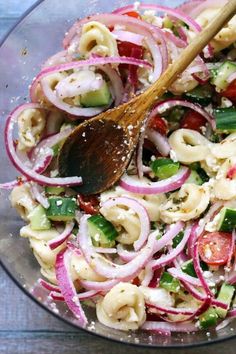 a bowl filled with pasta salad and a wooden spoon