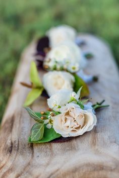 some white flowers are laying on a wooden plank outside in the grass and one flower is blooming