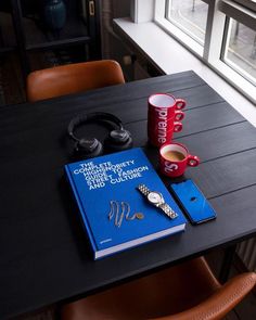 a table with headphones, coffee cup and book on it