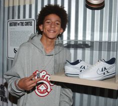 a young man standing in front of a shelf holding two pairs of shoes on it