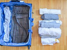 an open suitcase on the floor with clothes in it and one folded up to show what's inside