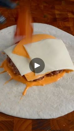 a burrito covered in cheese and sauce on top of a white plate