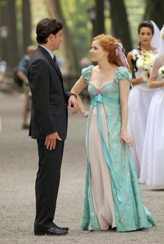 a man in a suit and tie standing next to a woman in a dress on the street