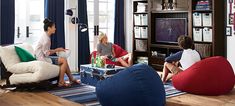 three people sitting on bean bag chairs in a living room watching tv and drinking beer