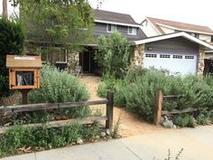 the front yard of a house with trees and bushes