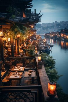 an outdoor dining area overlooking the water at night with lanterns lit up on tables and chairs