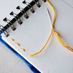 an open notebook with yellow thread and scissors