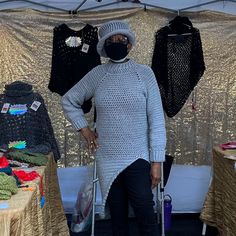 an elderly woman wearing a face mask and holding a crutch in front of a table with clothing on it