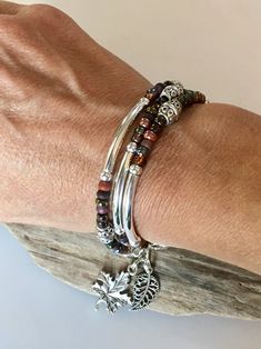 This Stunning Bohemian Style Bracelet/Necklace will be noticed and adored! Beautiful rich colors of browns, burgundy, wine, plum and Iris purple. Silver tube beads throughout with detailed Tibetan beads. High style bangle look! It's made to wrap around your wrist three times and connects with a lobster clasp. It has an extension chain to adjust to a tight or loose fit. You can choose a charm of your choice! Please see the last 3 Listing photos for your options. If choosing an Initial/Letter char Bohemian Multi-strand Beaded Bracelets With Silver Beads, Bohemian Silver Wrap Bracelet With Colorful Beads, Bohemian Brown Beaded Bracelets With Silver Beads, Bohemian Brown Bracelets With Silver Beads, Bohemian Beaded Stackable Bracelets, Bohemian Multi-strand Silver Beaded Bracelets, Bohemian Beaded Wrap Bracelet For Layering, Silver Bohemian Multi-strand Wrap Bracelet, Handmade Bohemian Beaded Bracelets For Layering