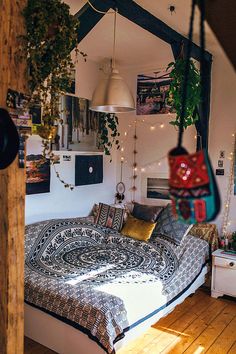 a bed sitting inside of a bedroom next to a wooden floor covered in pillows and blankets