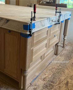 an unfinished kitchen island being built with wood and blue tape on the countertop,