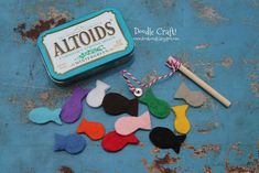 an assortment of felt fish next to a tin of altoids toothpaste on a blue surface